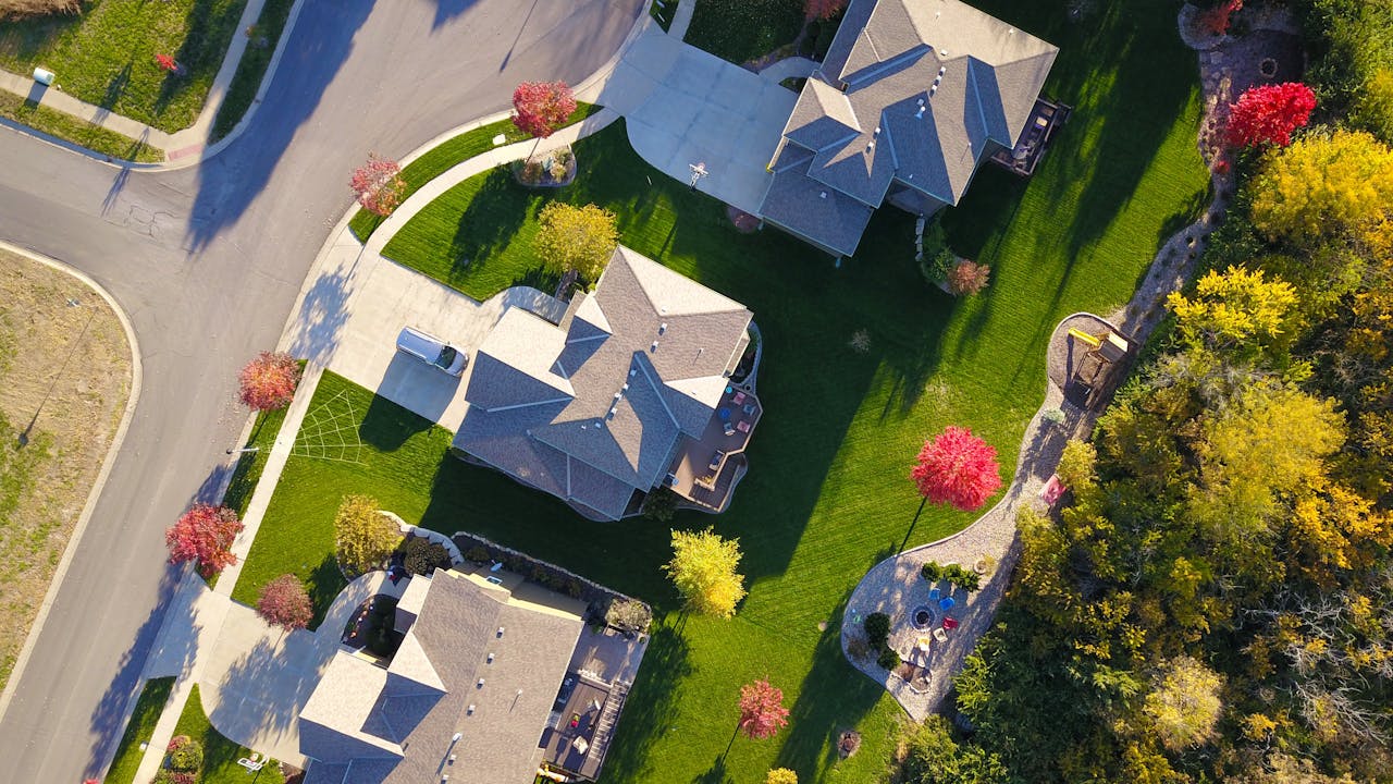 Services A picturesque aerial view showcasing suburban homes with vibrant gardens and tree-lined streets.
